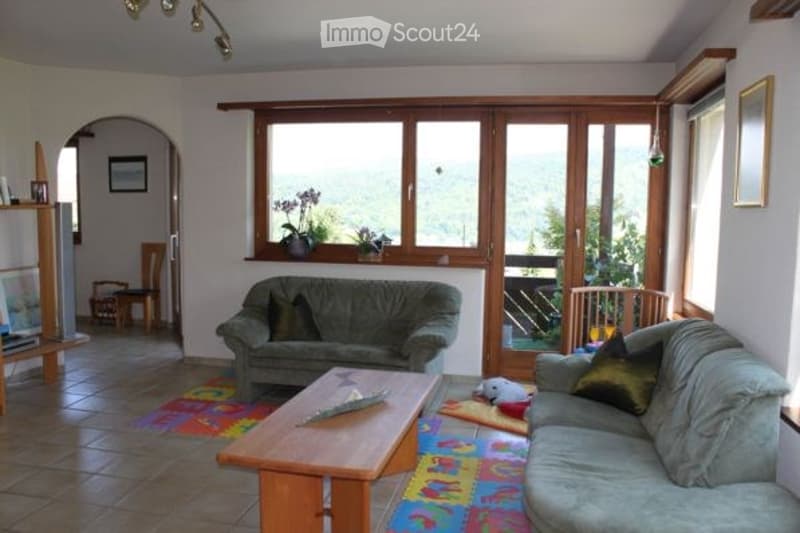 Living room with large windows offering a scenic view, two sofas, a coffee table, a small table, and a chair.