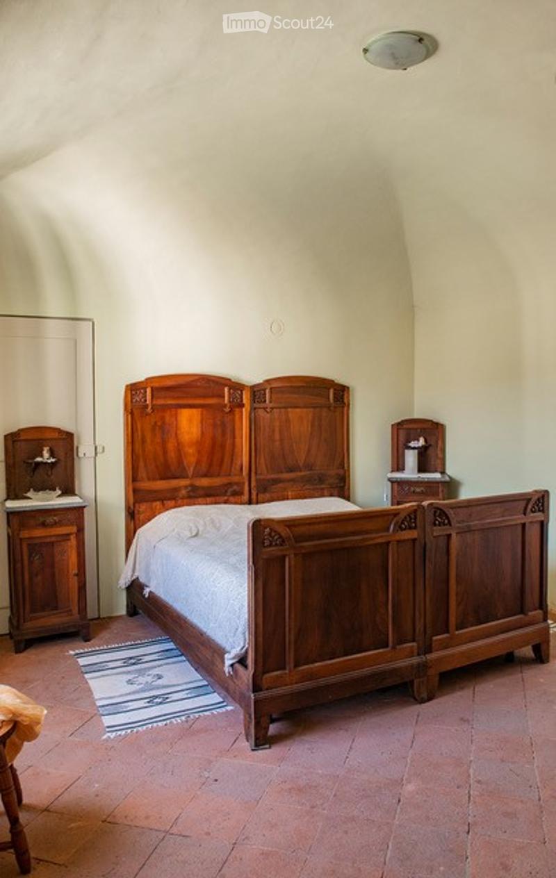 A bedroom with a wooden bed, nightstands, a mirror, and a small rug on the floor.