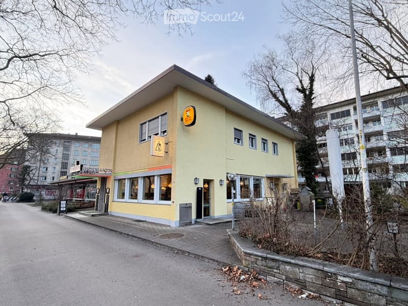 Two-story yellow building with a restaurant sign, windows, and a small entrance area.