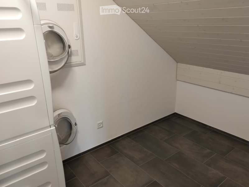 Modern bathroom with dark tiled floor, white walls, and built-in washing machine and dryer unit.