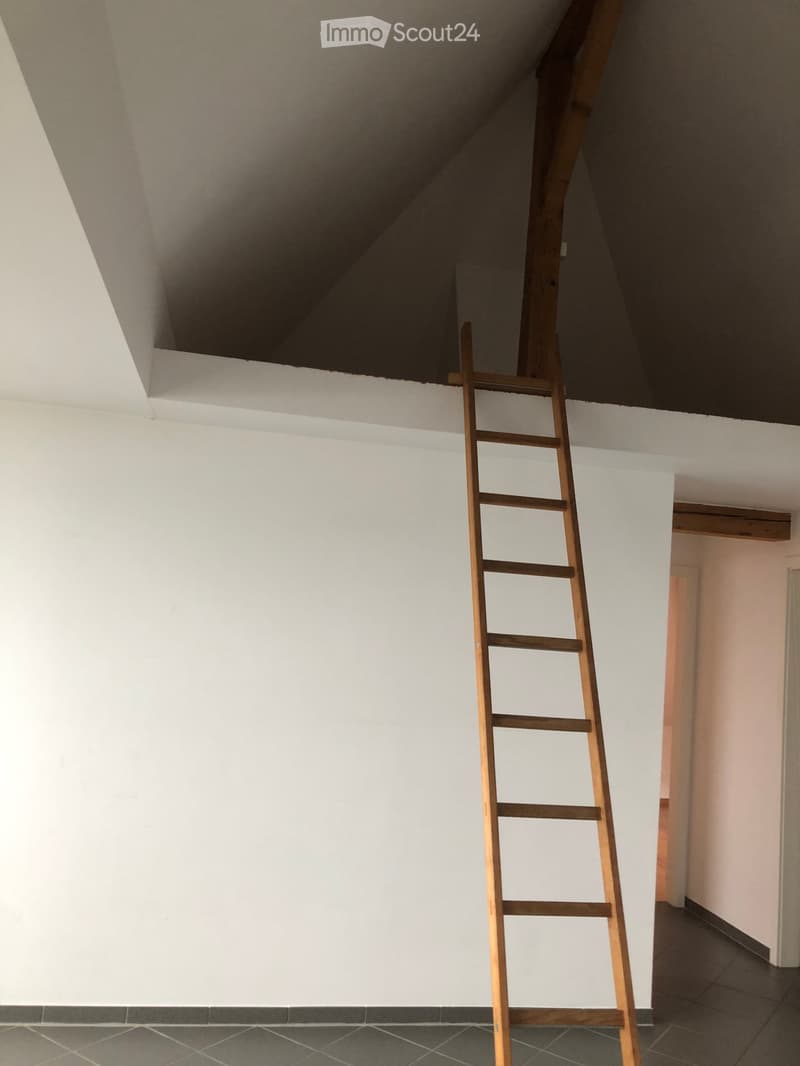 Empty room with white walls, tiled floor, and a wooden ladder leading to an attic space.