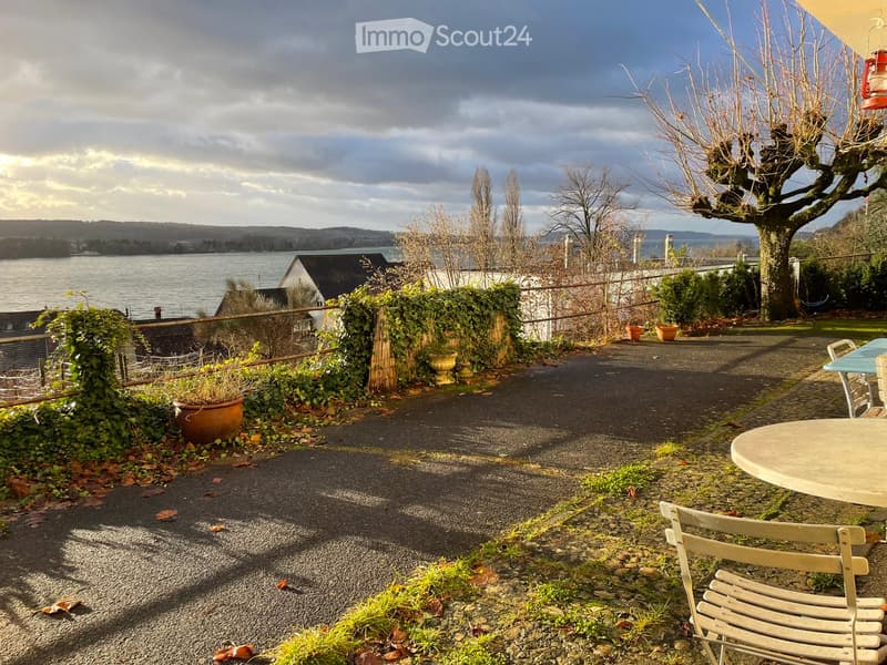 Garden area with gravel path, potted plants, outdoor furniture, and scenic lake view.