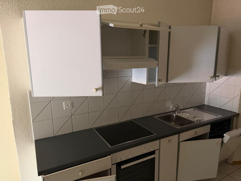Modern kitchen with white cabinets, black countertops, a sink, and an oven. The backsplash features a geometric tile pattern.