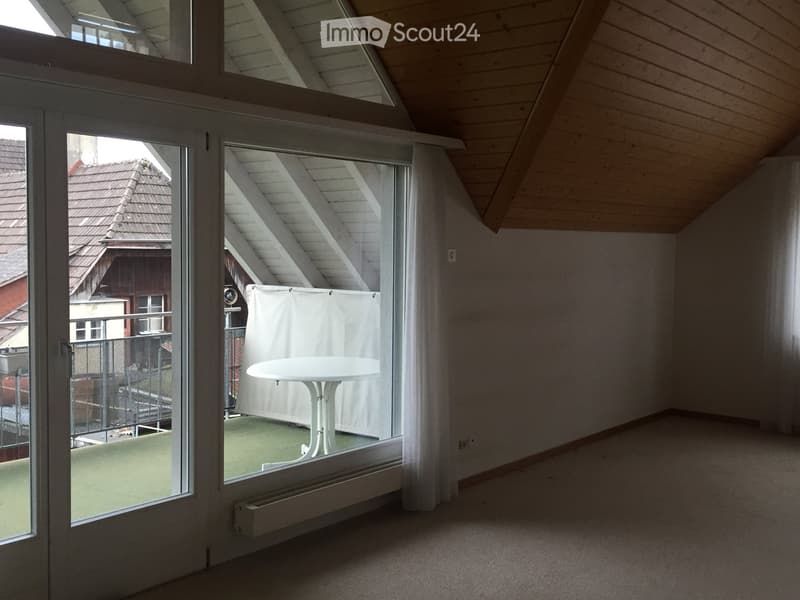 Bright, airy room with wooden slanted ceiling, large windows, and a white table near the window.