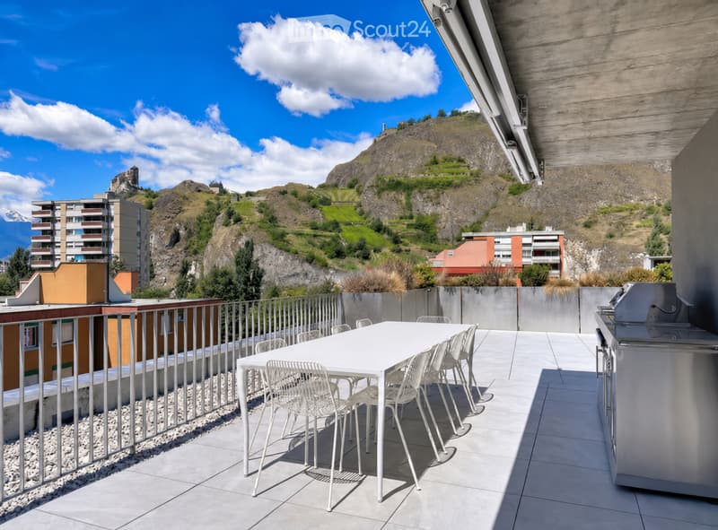 Modern rooftop terrace with a white dining table and chairs, a grill, and a scenic mountain view.