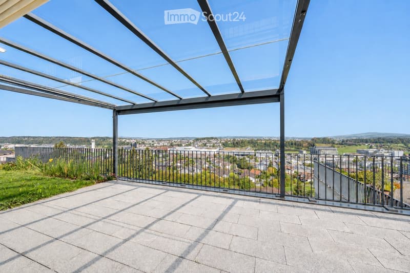 Modern rooftop terrace with a glass roof structure, metal railing, and expansive cityscape view.