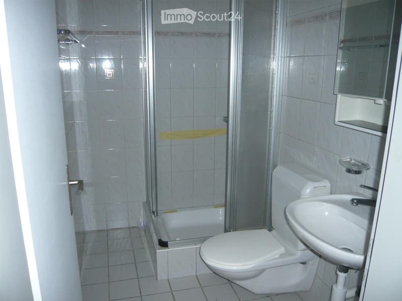 Modern bathroom with white tiles, a toilet, a sink, a bathtub, and a mirror above the sink.