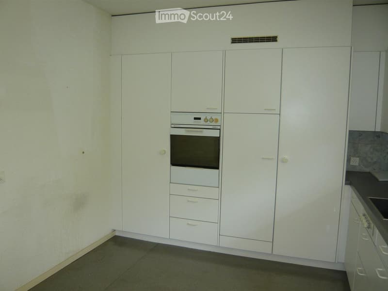 Modern kitchen with white cabinets, an integrated oven, and a tiled countertop.