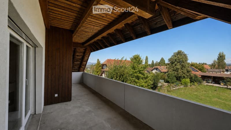 Balcony with wooden roof, concrete floor, and a view of a green landscape with trees and houses.