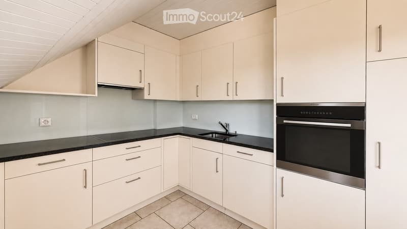 Modern kitchen with white cabinets, black countertops, a sink, and an oven.