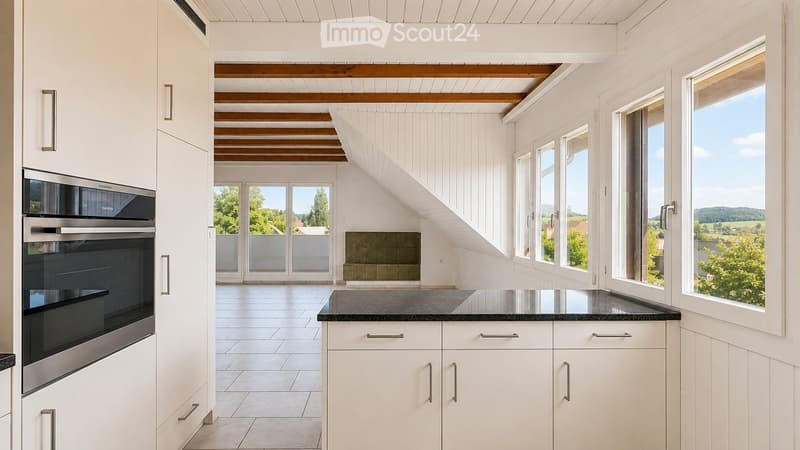 Modern kitchen with white cabinets, stainless steel oven, and large windows offering a scenic view.
