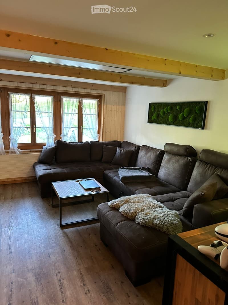 Modern living room with a dark brown sectional sofa, a glass coffee table, a wooden side table, and a decorative picture frame on the wall.