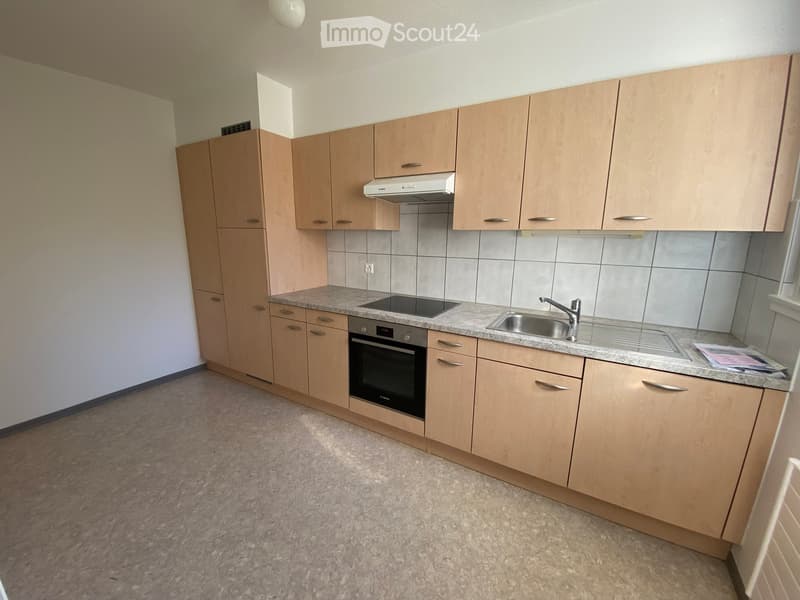 Modern kitchen with light wooden cabinets, granite countertop, stainless steel sink, and built-in oven.