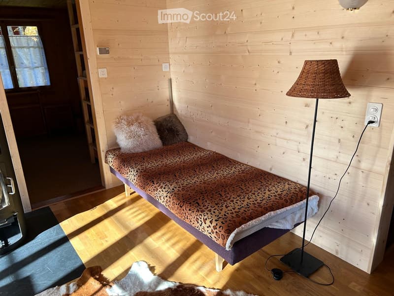 A small bed in a corner, lamp, wall outlet, hardwood floors, leopard print bedspread