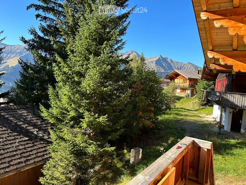 mountains, chalet-style buildings, wooden fence, trees, and grass