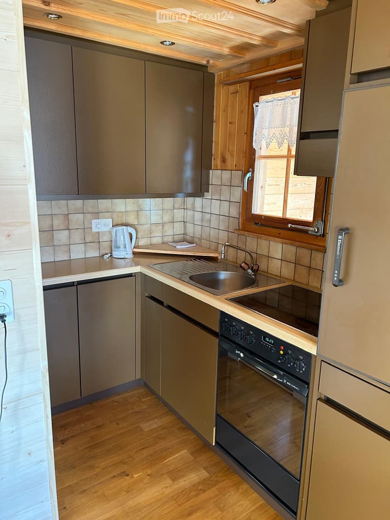 wooden kitchen area with stainless steel appliances, electric stove, sink, tiled backsplash, kitchen cabinets, outlet