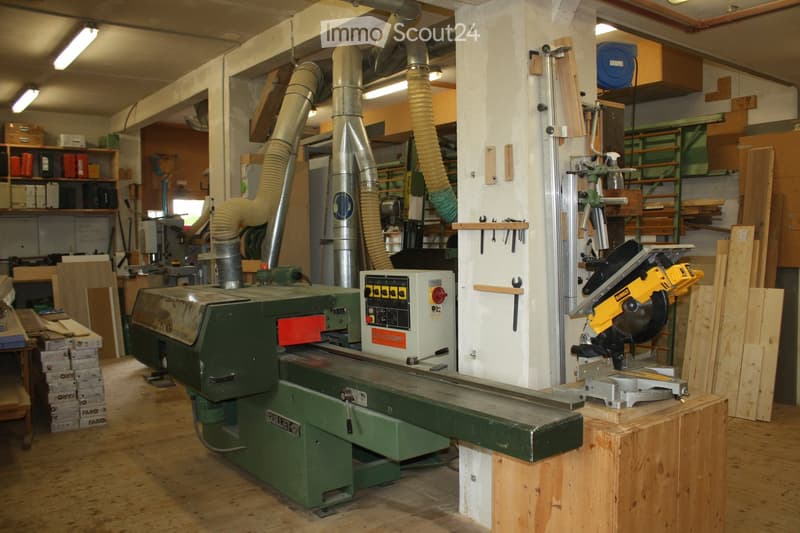 A well-equipped workshop with a table saw, circular saw, workbench, shelves, and various tools and materials.