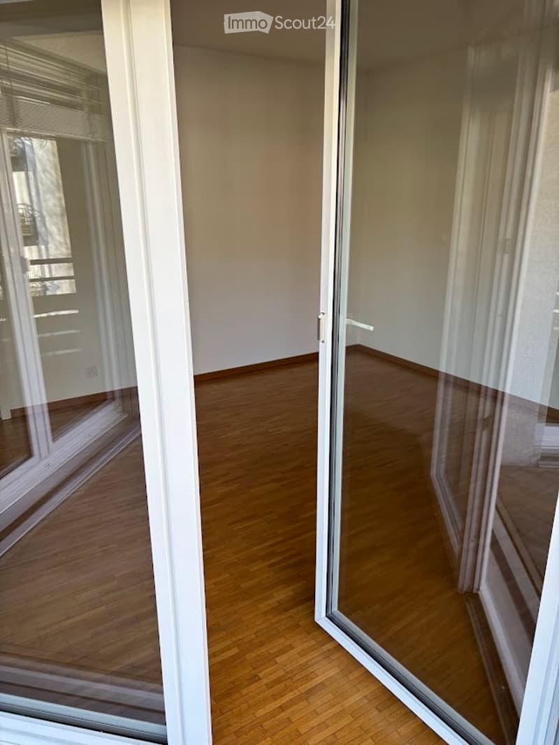 Empty room with wooden flooring and large glass sliding doors leading to a balcony or outdoor area.