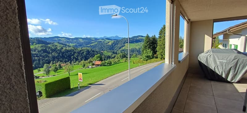 Balcony with a scenic mountain view, tiled floor, covered grill, and a street below.