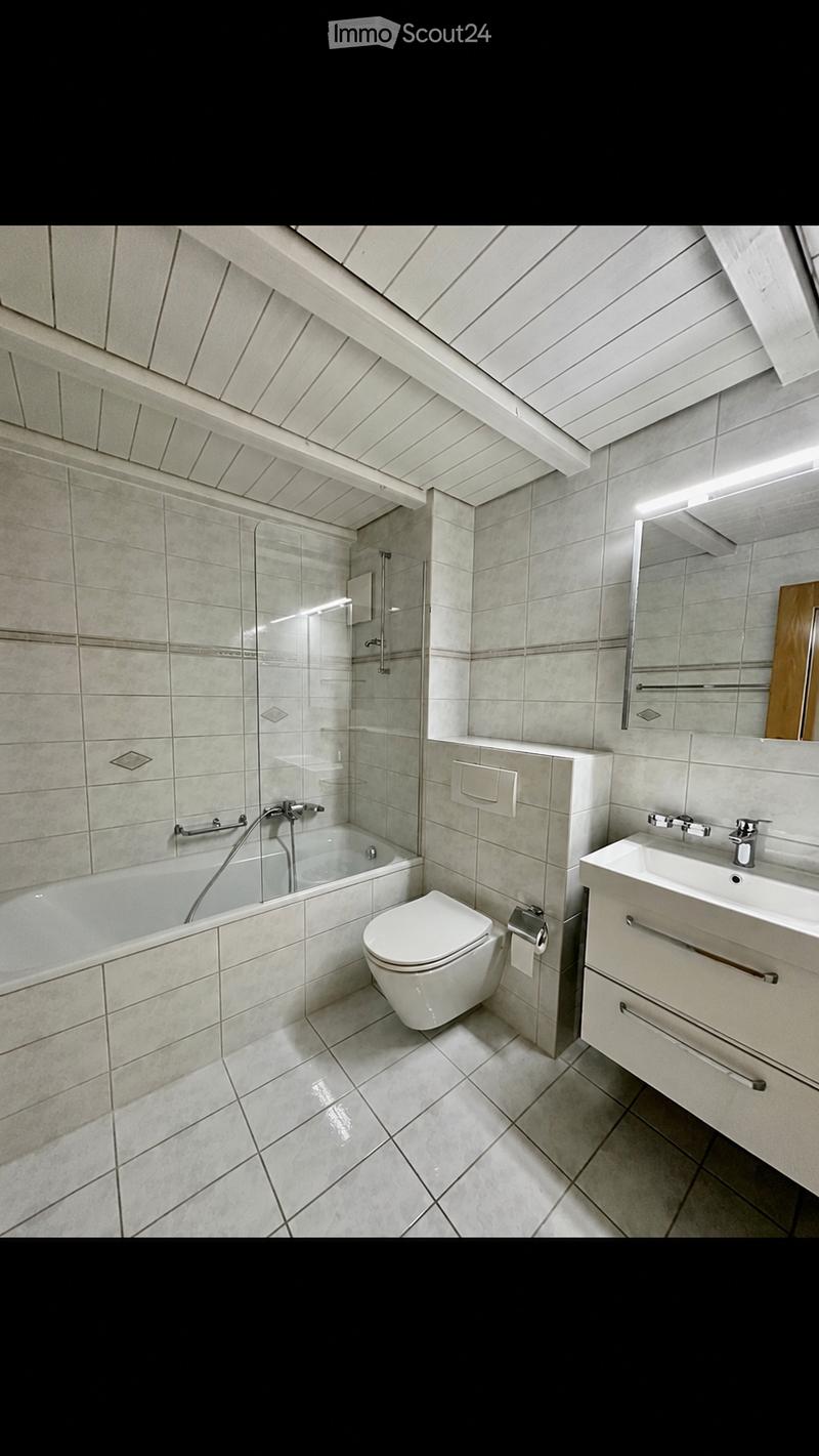 Modern bathroom with a bathtub, toilet, sink, and shower stall. The space features tiled walls and floor, a large mirror above the sink, and sleek fixtures.