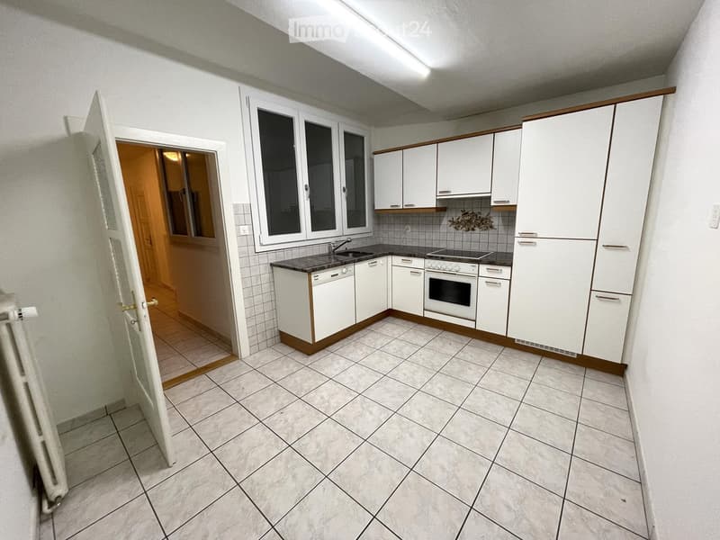 Modern kitchen with white cabinets, tiled floor, and built-in appliances including an oven, dishwasher, and sink.