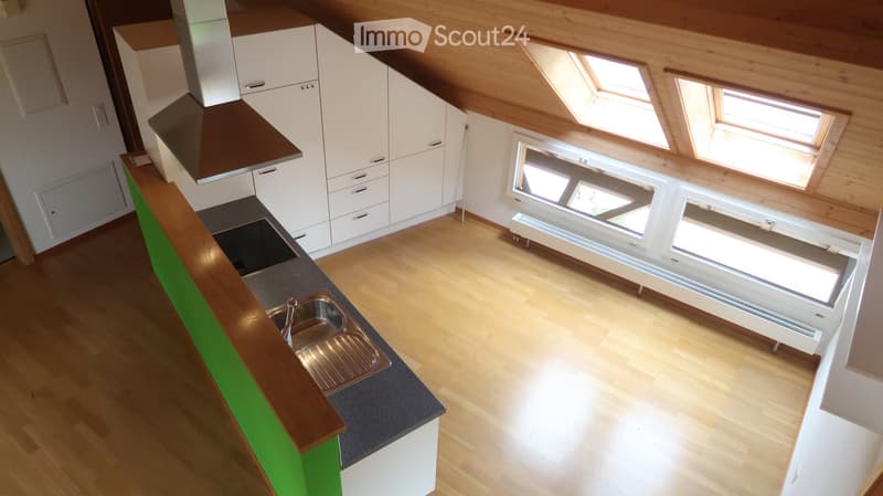 Modern kitchen with white cabinets, wooden countertops, and a stainless steel sink. The room features wooden flooring and large windows, including skylights, allowing ample natural light.