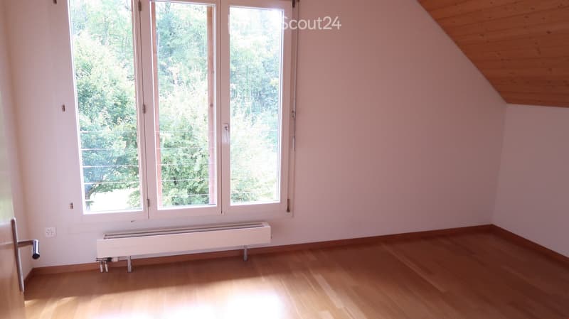 Empty room with wooden flooring, white walls, large windows, and a radiator. No furniture or equipment present.