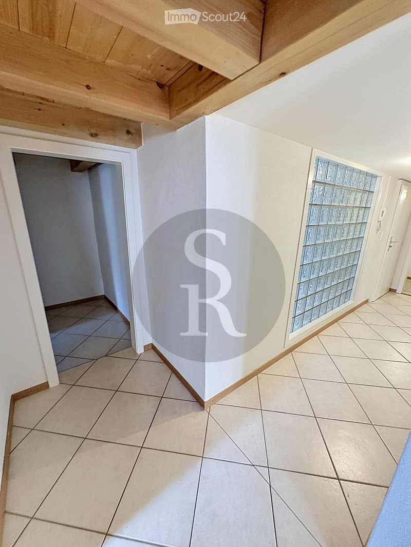 Empty hallway with tiled flooring, white walls, and a frosted glass window on one side.