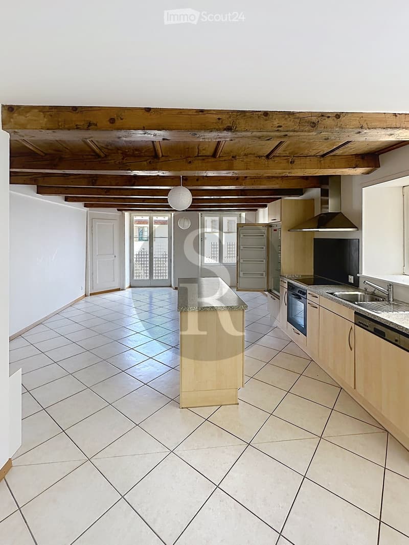 Bright, open kitchen with tiled flooring, wooden cabinets, stainless steel appliances, and a central island.