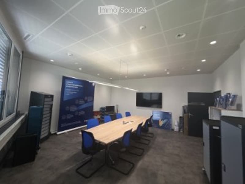 Conference room with a long wooden table, blue chairs, a large screen, and cabinets.