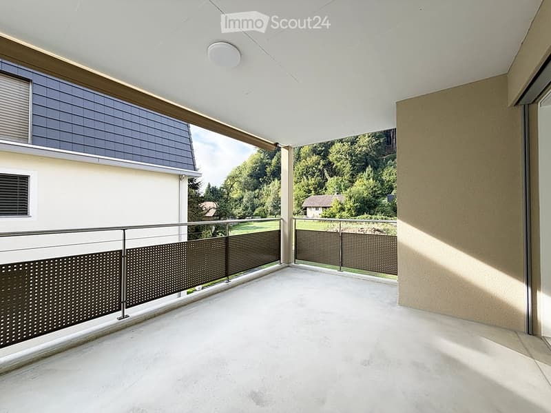 Spacious balcony with modern metal railing, white ceiling, and scenic view of greenery and a neighboring house.