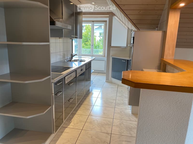 Modern kitchen with stainless steel appliances, marble tiles, and a wooden island counter.