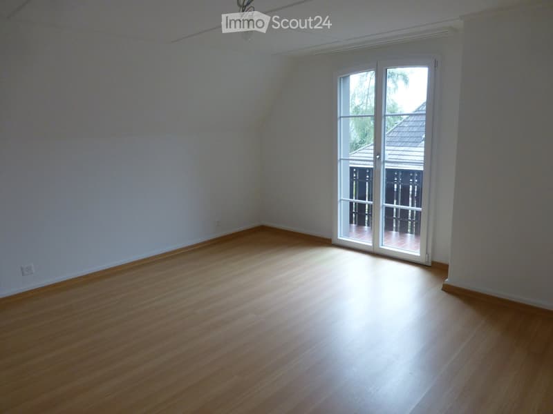 Empty room with wooden flooring, white walls, and a large sliding glass door leading to an outdoor area.