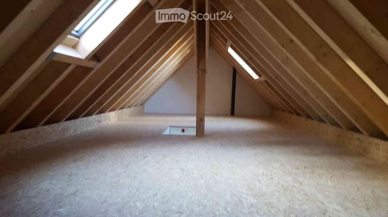 unfinished attic room with sloping ceiling, two windows, and one pipe opening on the floor