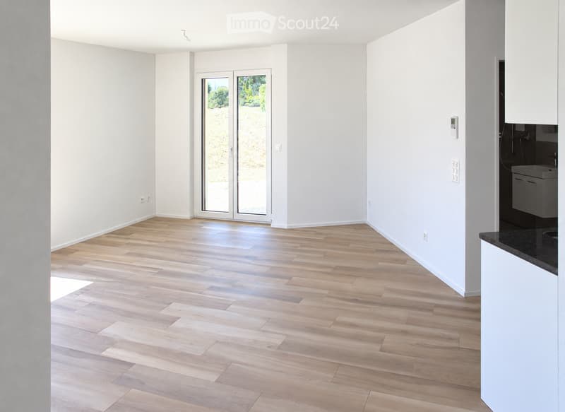 Empty room with light wooden flooring, white walls, and a large glass sliding door leading to an outdoor area. The room is unfurnished with no visible furniture or equipment.