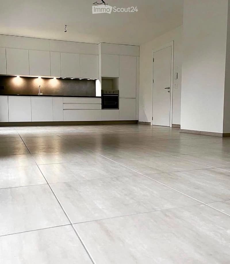 Empty kitchen with white cabinets, stainless steel appliances, and tiled floor. No furniture or equipment present.