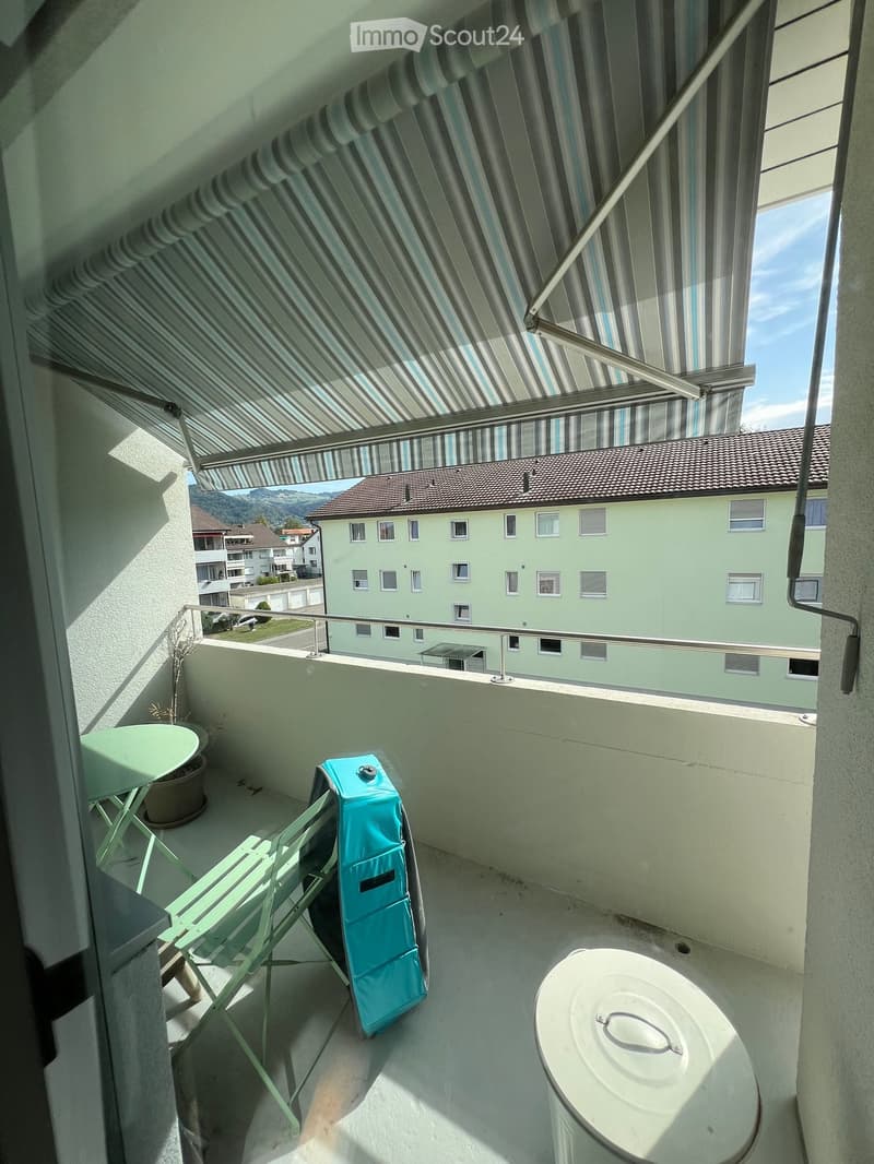 Balcony with a table, chair, potted plant, and a covered area with a retractable awning.