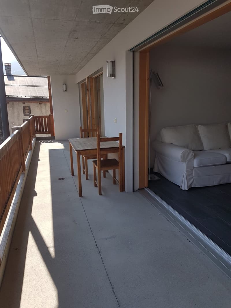 Balcony with a sofa, small table, and chairs, connected to an indoor space.