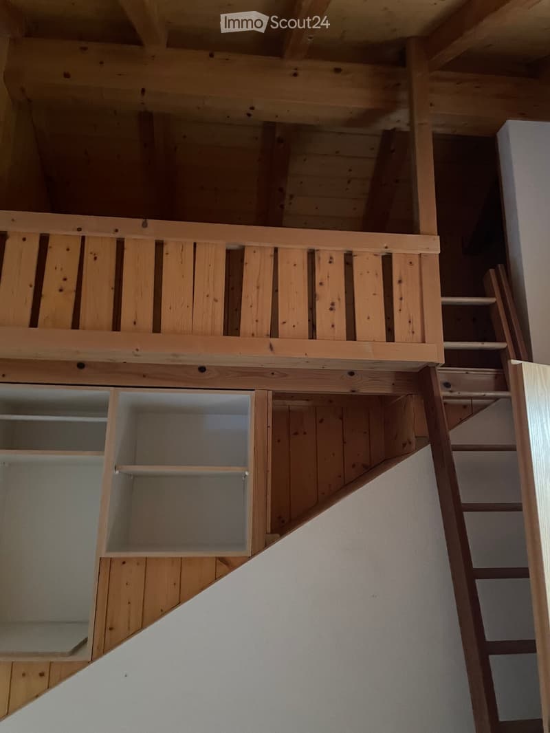 Wooden staircase with open wooden railings and built-in storage shelves on the wall.