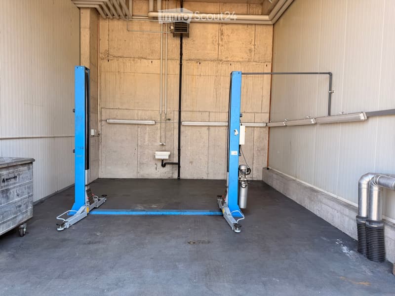 Empty room with concrete walls, industrial floor, and visible pipes and equipment.