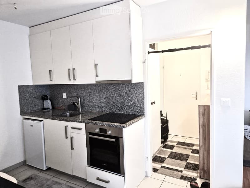 Compact kitchen with white cabinets, black granite countertop, built-in oven, and a dishwasher