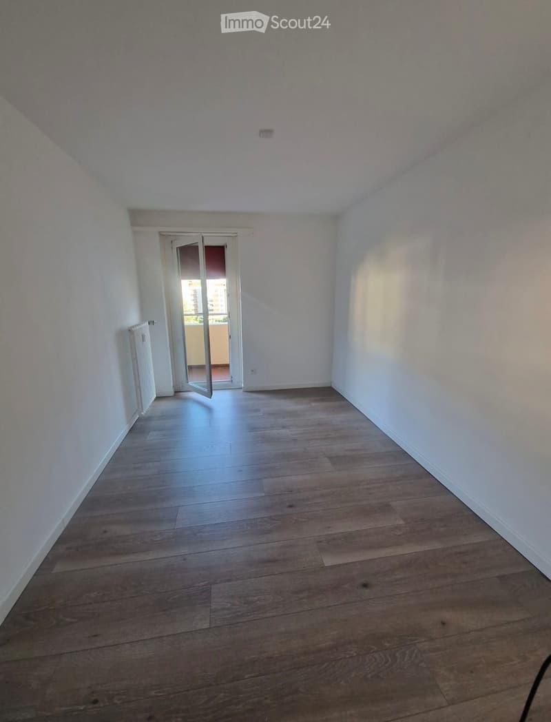 Empty room with wooden flooring, white walls, and a door leading to a balcony.