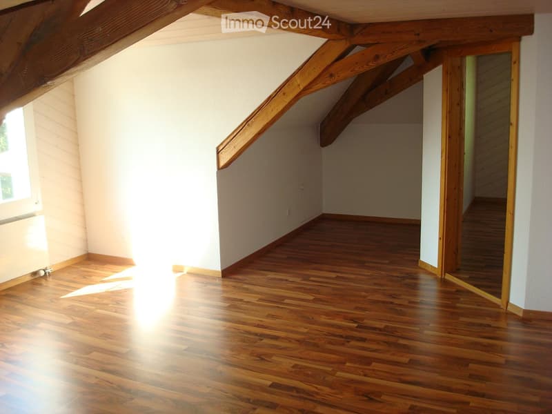 empty room with wooden floors, wooden beams, white walls, small window, small door
