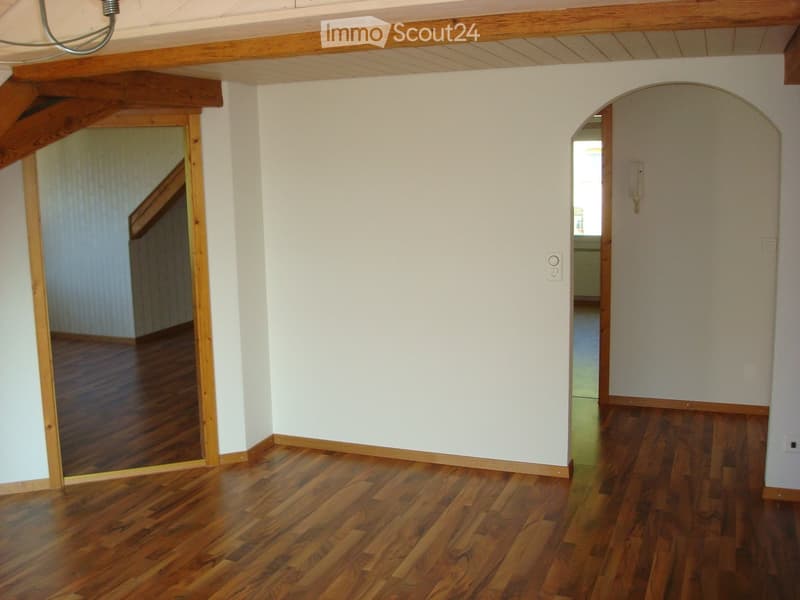 Wooden floors, white walls, a wooden archway, wooden beam ceiling, doors on both sides