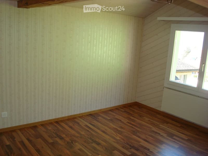 Hardwood floors, white walls, single window with white frames, wall radiator, power outlet