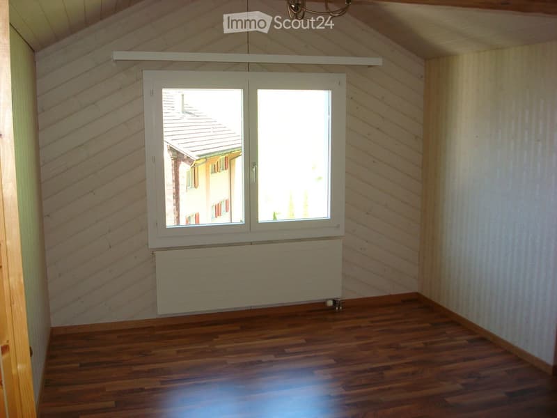 empty room with wooden floor, white walls, large window, and a white radiator