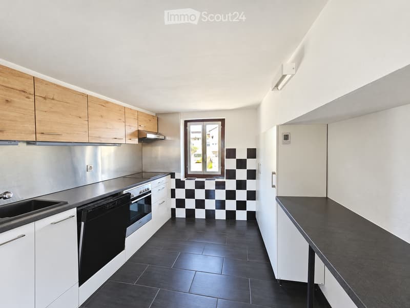 Modern kitchen with white cabinets, stainless steel appliances, black tiled floor, and a window with a view.