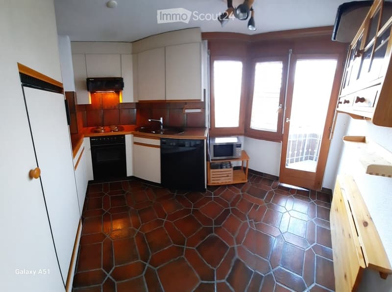 Modern kitchen with white cabinets, stainless steel appliances, and a brown tiled floor. Features include a refrigerator, oven, dishwasher, microwave, and a sink with a faucet.