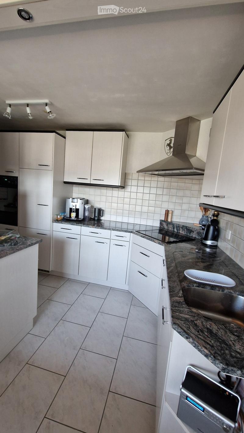 Modern kitchen with white cabinets, granite countertops, and stainless steel appliances including a coffee maker, oven, and sink.