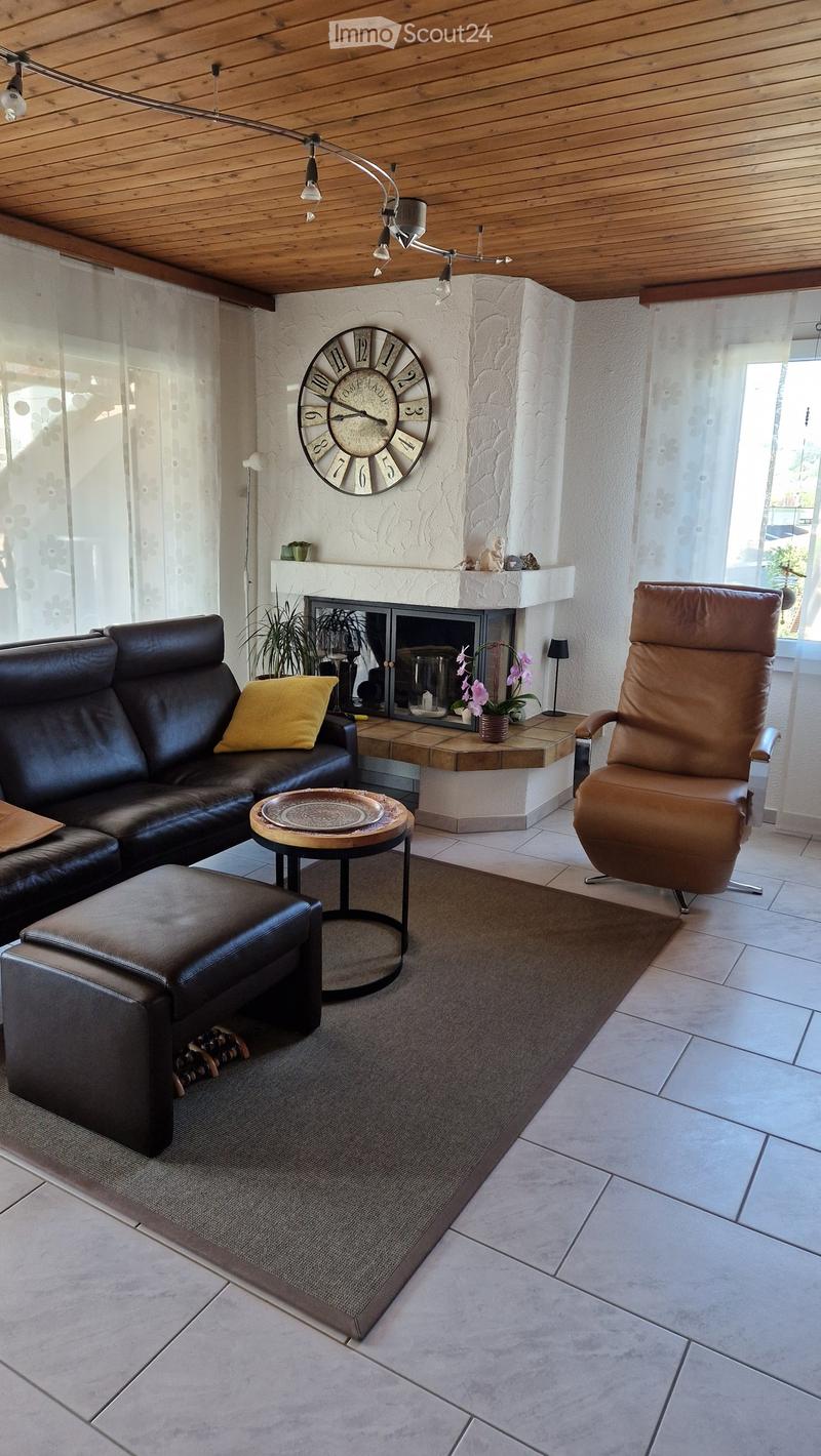 Modern living room with a leather sofa, ottoman, armchair, coffee table, fireplace, and decorative items.